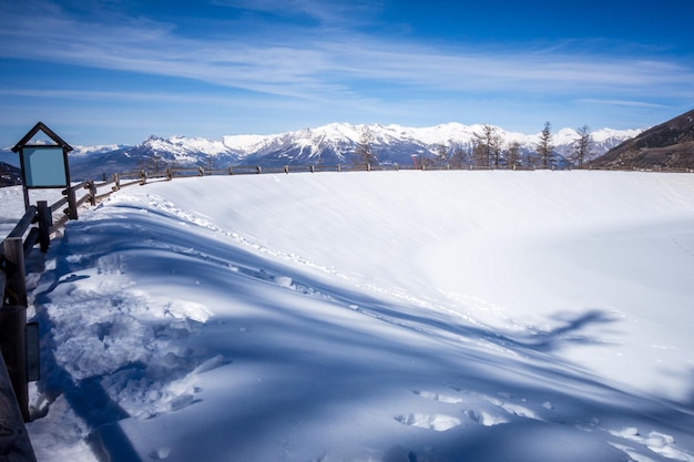 Mountain landscape under snow in winter and frozen lake