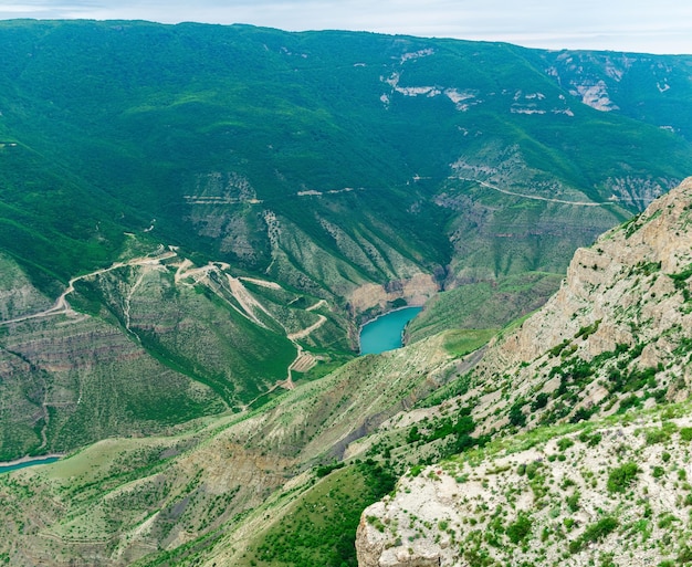 Mountain landscape view of a huge canyon with rocky green slopes and blue river at the bottom