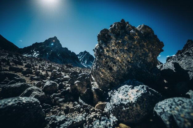 A mountain landscape with rocks and a blue sky with the sun shining on it.