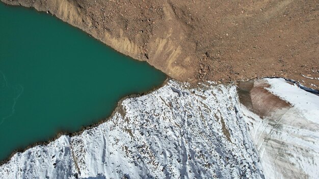 A mountain moraine lake with emerald water looks like a mirror. Top view from a drone.