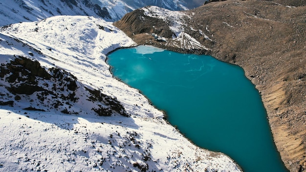 A mountain moraine lake with emerald water looks like a mirror. Top view from a drone.