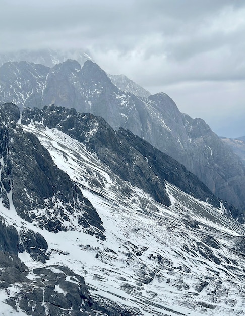 A mountain range with snow on the mountains and a cloudy sky