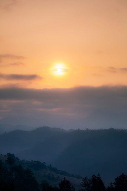 Mountain range with visible silhouettes through the morning colorful fog.