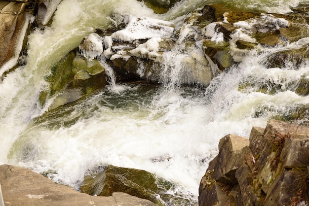 Mountain river in a beautiful winter green coniferous forest on the slopes of the mountains Outdoor recreation in the winter season