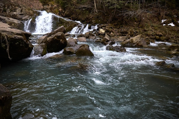 Mountain river narrow rocks and forming cascades Rural area of ukrainian village in mountains Early spring in Carpathian Mountains