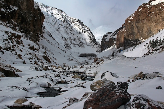 Mountain stream in the ravine between the snowcapped mountains of the Caucasus Mountain Elbrus