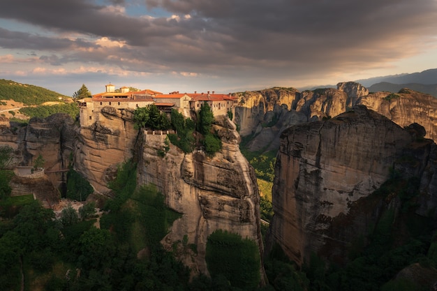 Mountain valley at sunset in Greece with bizarre cliffs and an old monastery on top of a cliff