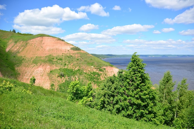 A mountain with red clay and the view to the Volga river with blue sky and white clouds