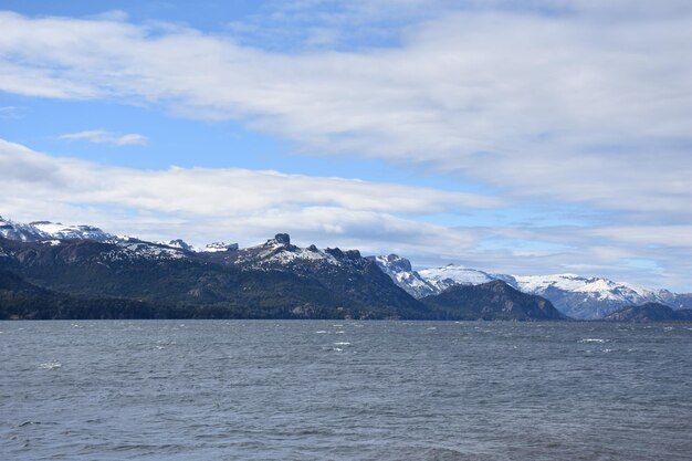 a mountain with snow on it and a blue sky with clouds