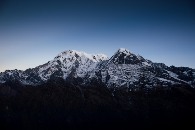 A mountain with snow on it and the sun is setting.