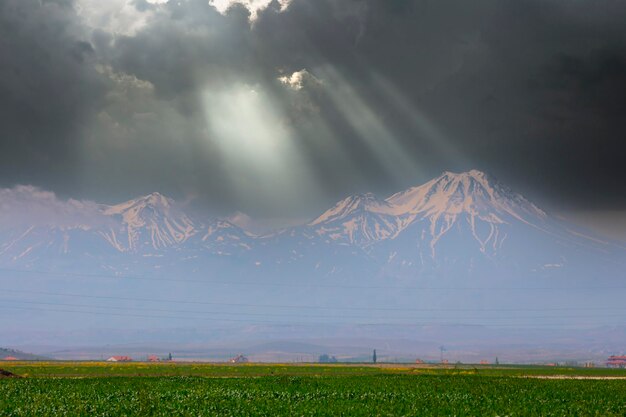 a mountain with the sun shining through the clouds