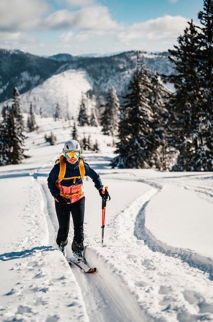 Mountaineer backcountry ski walking ski woman alpinist in the mountains Ski touring in alpine landscape with snowy trees Adventure winter sport Freeride skiing