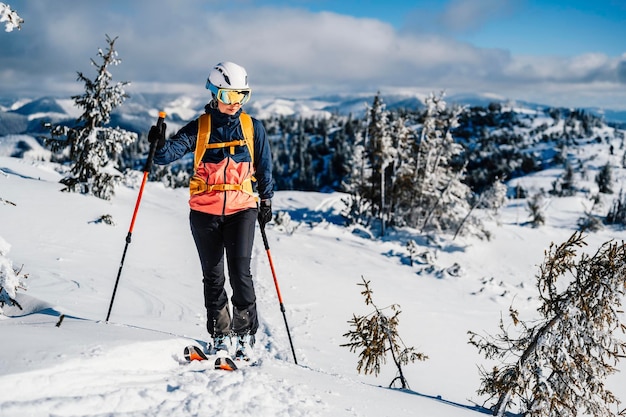 Mountaineer backcountry ski walking ski woman alpinist in the mountains Ski touring in alpine landscape with snowy trees Adventure winter sport Freeride skiing