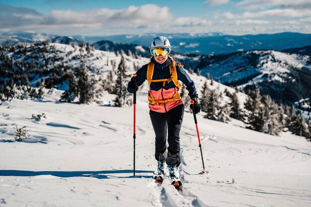 Mountaineer backcountry ski walking ski woman alpinist in the mountains Ski touring in alpine landscape with snowy trees Adventure winter sport Freeride skiing