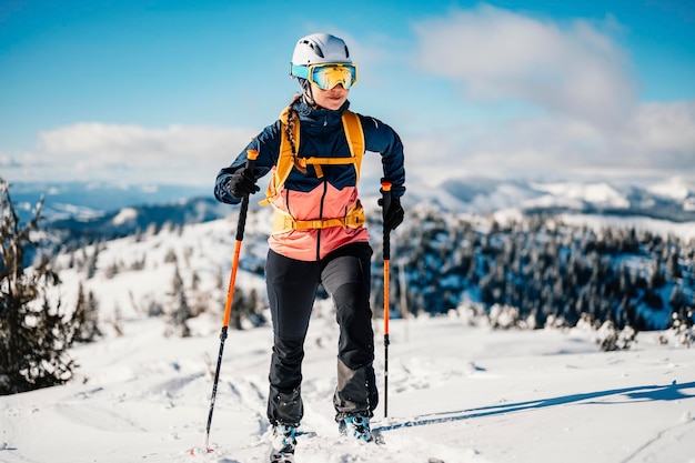 Mountaineer backcountry ski walking ski woman alpinist in the mountains Ski touring in alpine landscape with snowy trees Adventure winter sport Freeride skiing