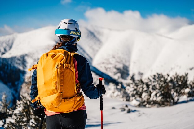 Mountaineer backcountry ski walking ski woman alpinist in the mountains Ski touring in alpine landscape with snowy trees Adventure winter sport Freeride skiing