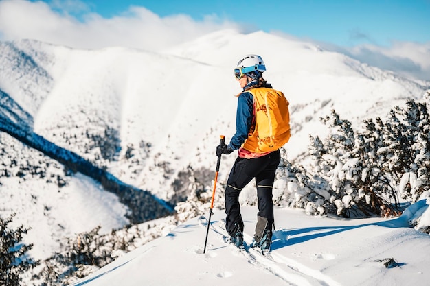 Mountaineer backcountry ski walking ski woman alpinist in the mountains Ski touring in alpine landscape with snowy trees Adventure winter sport Freeride skiing