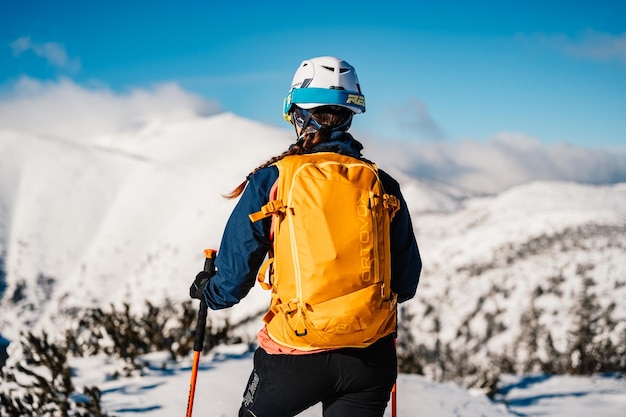 Mountaineer backcountry ski walking ski woman alpinist in the mountains Ski touring in alpine landscape with snowy trees Adventure winter sport Freeride skiing