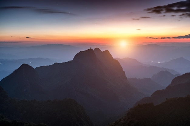 Mountaineer man standing on peak mountain range at sunset