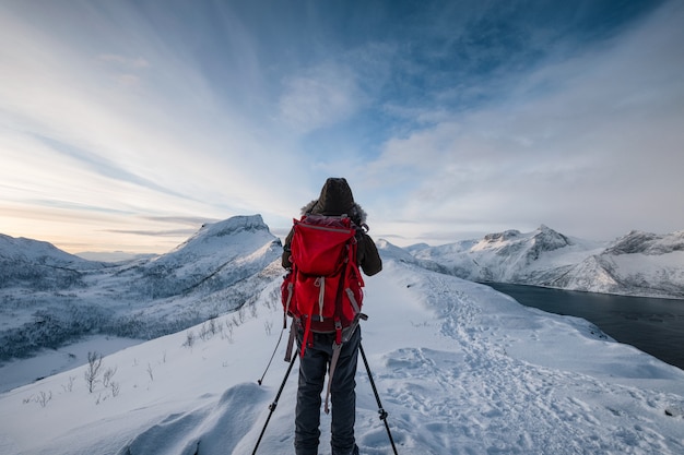 Mountaineer with backpack on mountain peak in winter