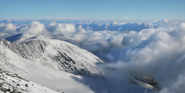 In the mountains above the clouds. Snow-covered slopes and peaks.