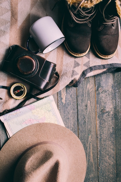 mountains hiking stuff on wooden floor Boots camera hat map compass 