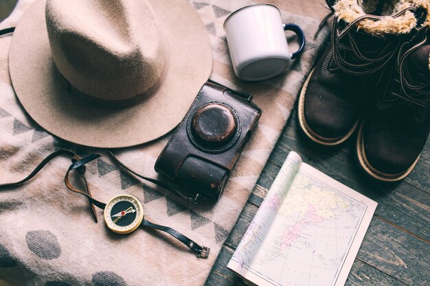 mountains hiking stuff on wooden floor Boots camera hat map compass 