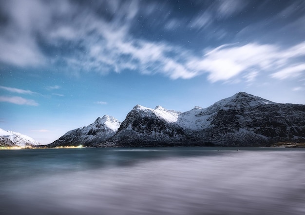 Mountains and reflections on water at night Winter landscape The sky with stars and clouds in motion Nature as a background Norway travel