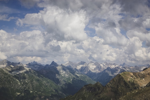 Mountains scene with dramatic cloudy sky in national park of Dombay, Caucasus, Russia. Summer landscape and sunny day