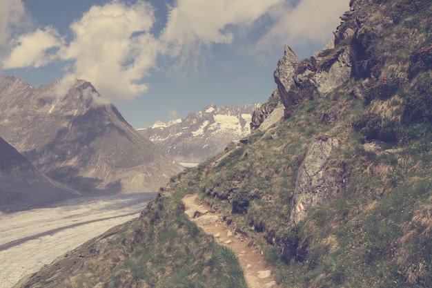 Mountains scenes, walk through the great Aletsch Glacier, route Aletsch Panoramaweg in national park Switzerland, Europe. Summer landscape, cloudy sky and sunny day