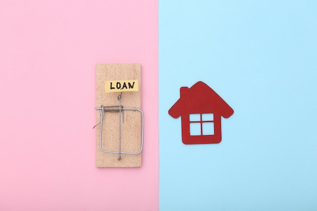 Mousetrap with loan bait and house on blue-pink pastel background. Trap, risks or deception concept