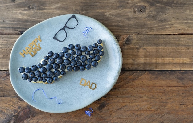 Moustacheshaped cake with blueberries and decoration Copy space