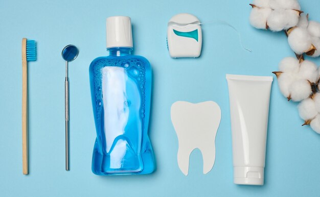 Mouthwash toothpaste tube dental floss and medical mirror on a blue background