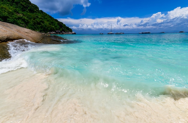 Movement of fine white sand with clear sea with white cloudy and blue sky at Similan Island