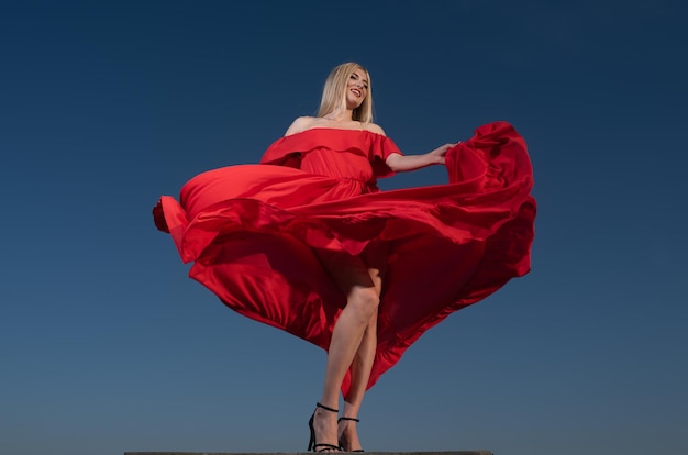 Movement girl in red dress on sky beautiful young woman in fashion dress outdoor sexy and sensual fe