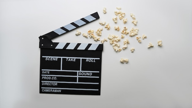 Movie clapboard and popcorn on white background.