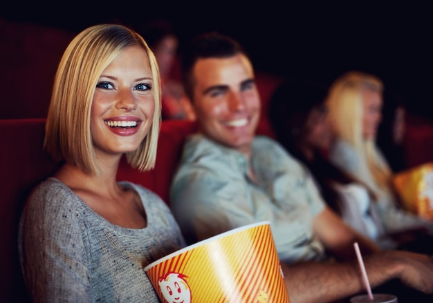 Movie popcorn and smile with woman on a date with man at cinema interior or theater event Happy film or show screen with couple eating snacks and watching together at night time