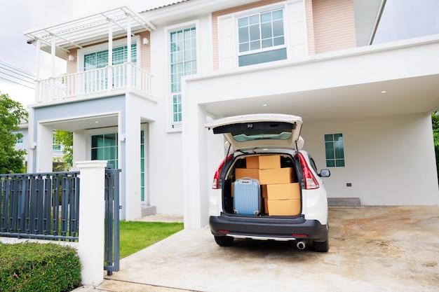 Moving Day Many cardboard boxes and luggage in car that parking front of beautiful new house