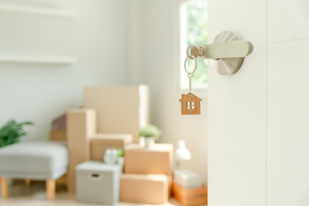 Moving house relocation key house keychain in new apartment inside the room was a cardboard box containing personal belongings and furniture move in the apartment or condominium Second hand