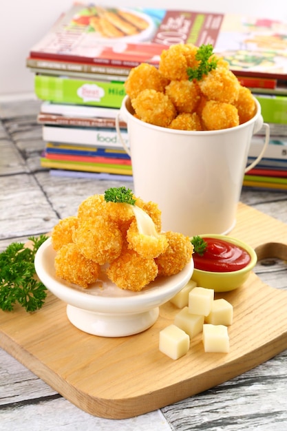 Mozzarella nuggets with ketchup on cutting board at home