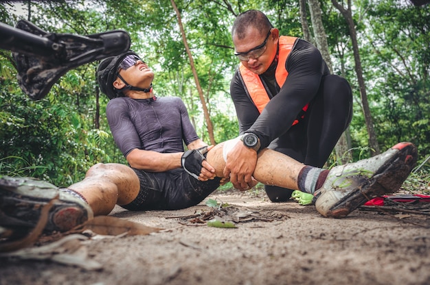 MTB mountain bike accident and first aid : Biker crash crashes, injuring knee and leg, First aid to help mountain biker in accident. Mountain bike athlete first aid team injured during race accident.