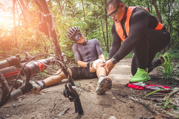 MTB mountain bike accident and first aid : Biker crash crashes, injuring knee and leg, First aid to help mountain biker in accident. Mountain bike athlete first aid team injured during race accident.