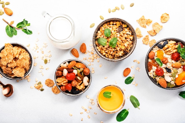 Muesli bowl organic ingredients for healthy breakfast Granola nuts dried fruits oatmeal whole grain flakes on white background Copy space banner