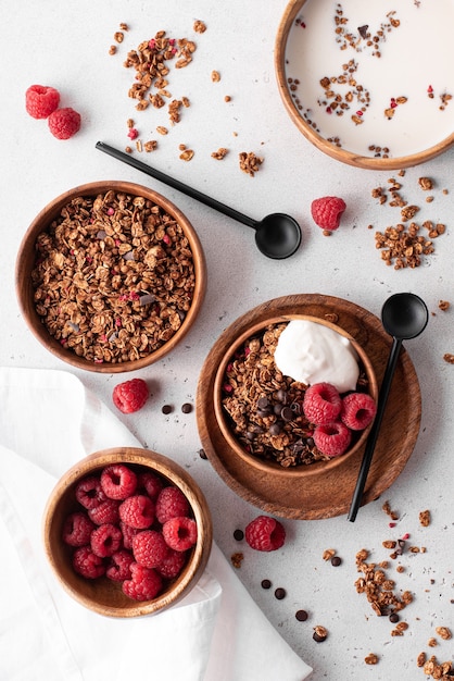 Muesli with chocolate, nuts and fresh raspberries in wooden bowls, top view