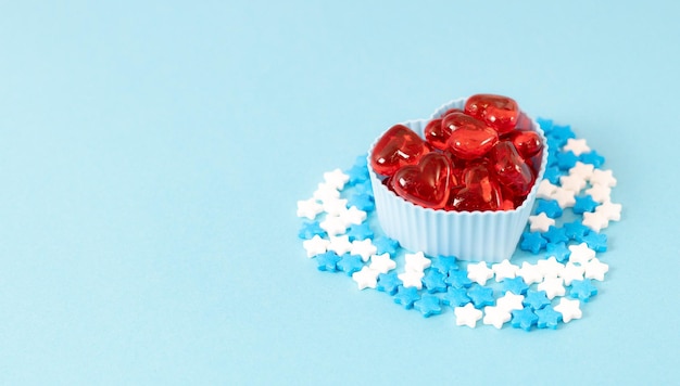 Muffin molds with red hearts and candy sprinkles on blue