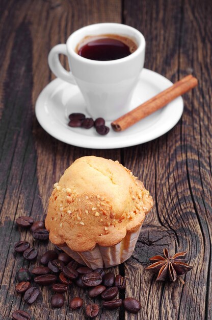 Muffin with nuts and cup of coffee on wooden table