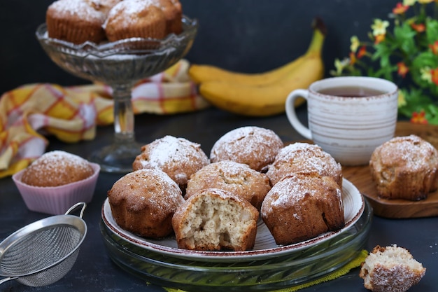 Muffins with bananas are located on plates against a dark background