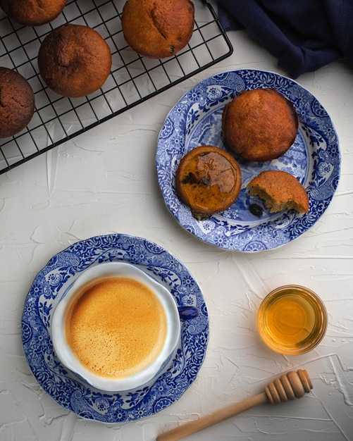 Muffins with raisins served with coffee and honey for restaurant on white backgroundTop view