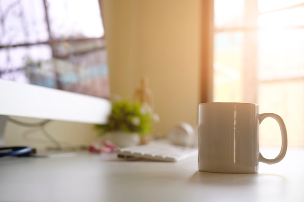 Mug of coffee on office workplace with morning coffee concept.