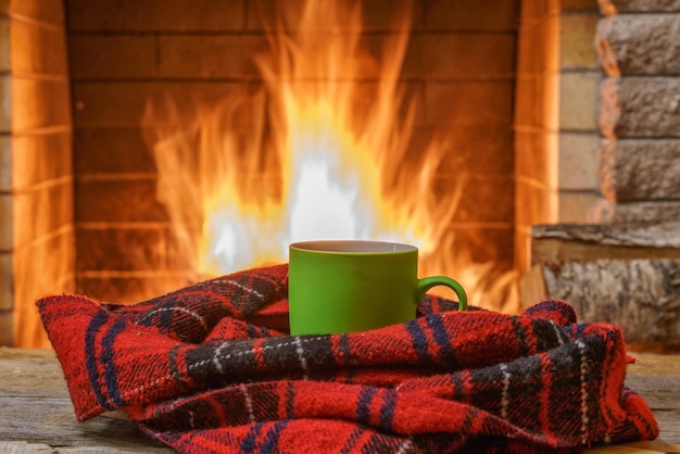 A mug of tea and woolen thing near a cozy fireplace in a country house